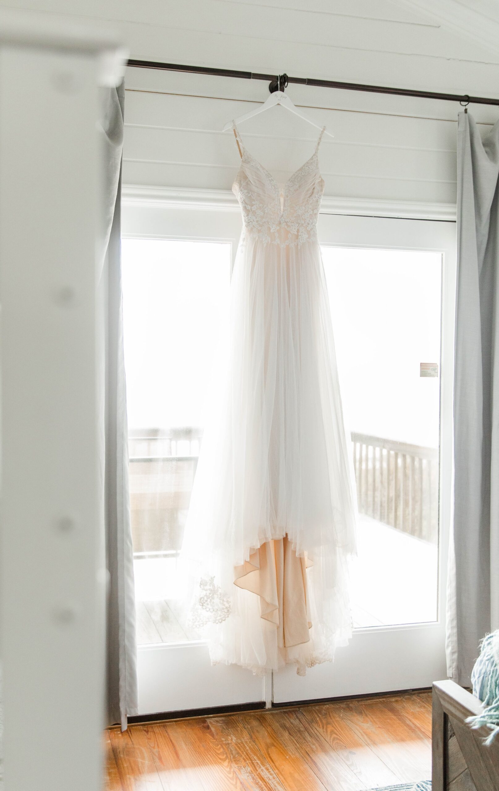 Wedding dress hanging in a window for a beach destination wedding