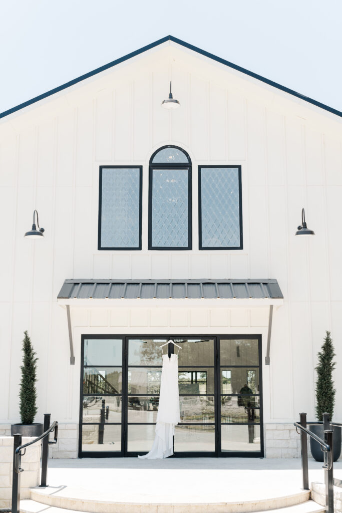 wedding venue dallas texas with wedding dress hanging on the front door in sunny weather