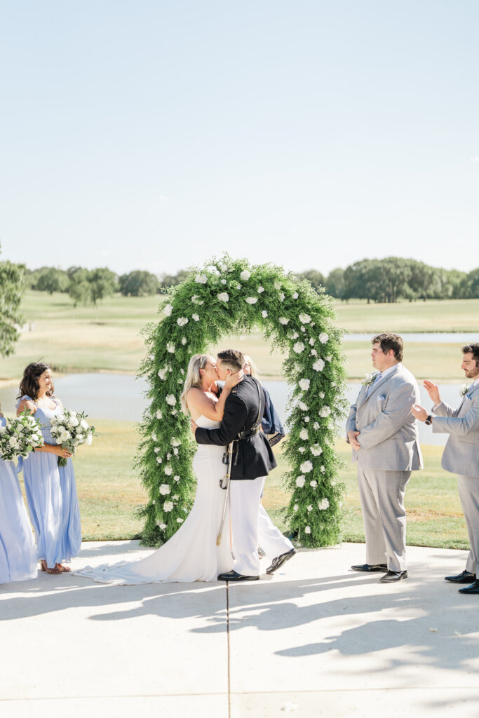bride and groom have their first kiss under a bright July sky with rolling green hills behind them 