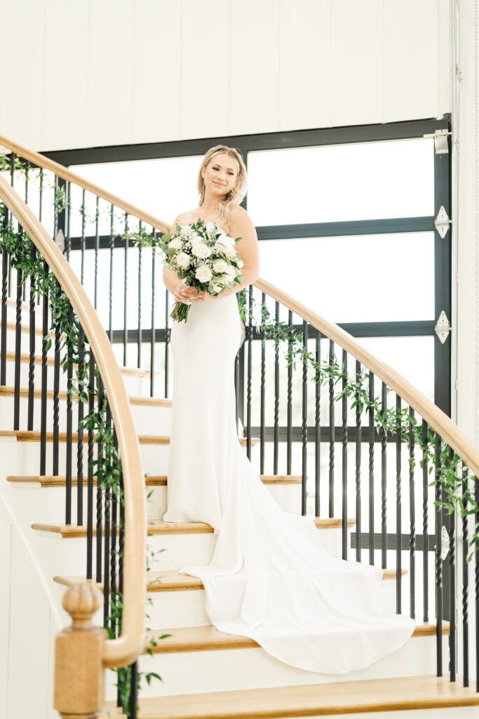 a bride holding a bouquet standing on a spiral staircase in a wedding venue dallas texas