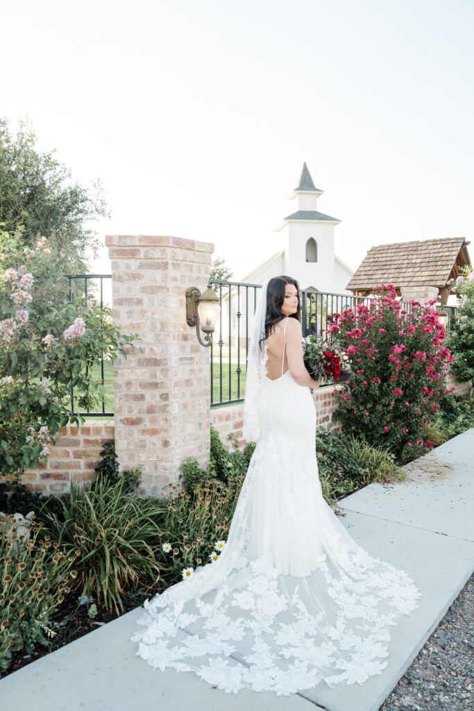 bride at lubbock wedding venue in long dress with train in front of a chapel 