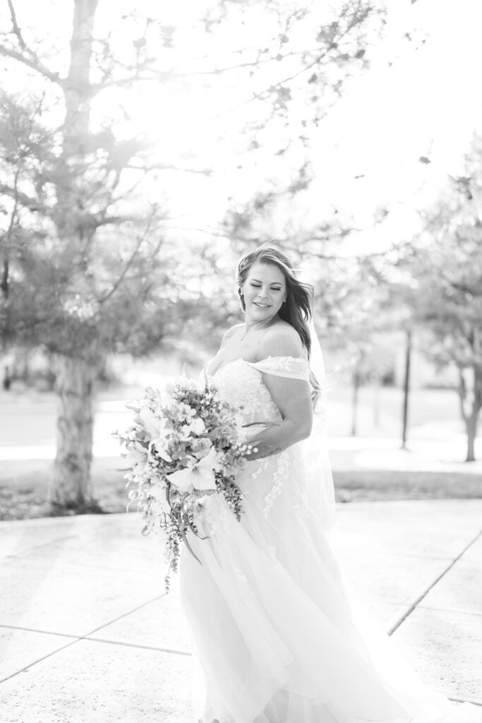 Bridal session in black and white with bride holding a cascading bouquet with lilies, wearing a lacy dress with draping sleeves