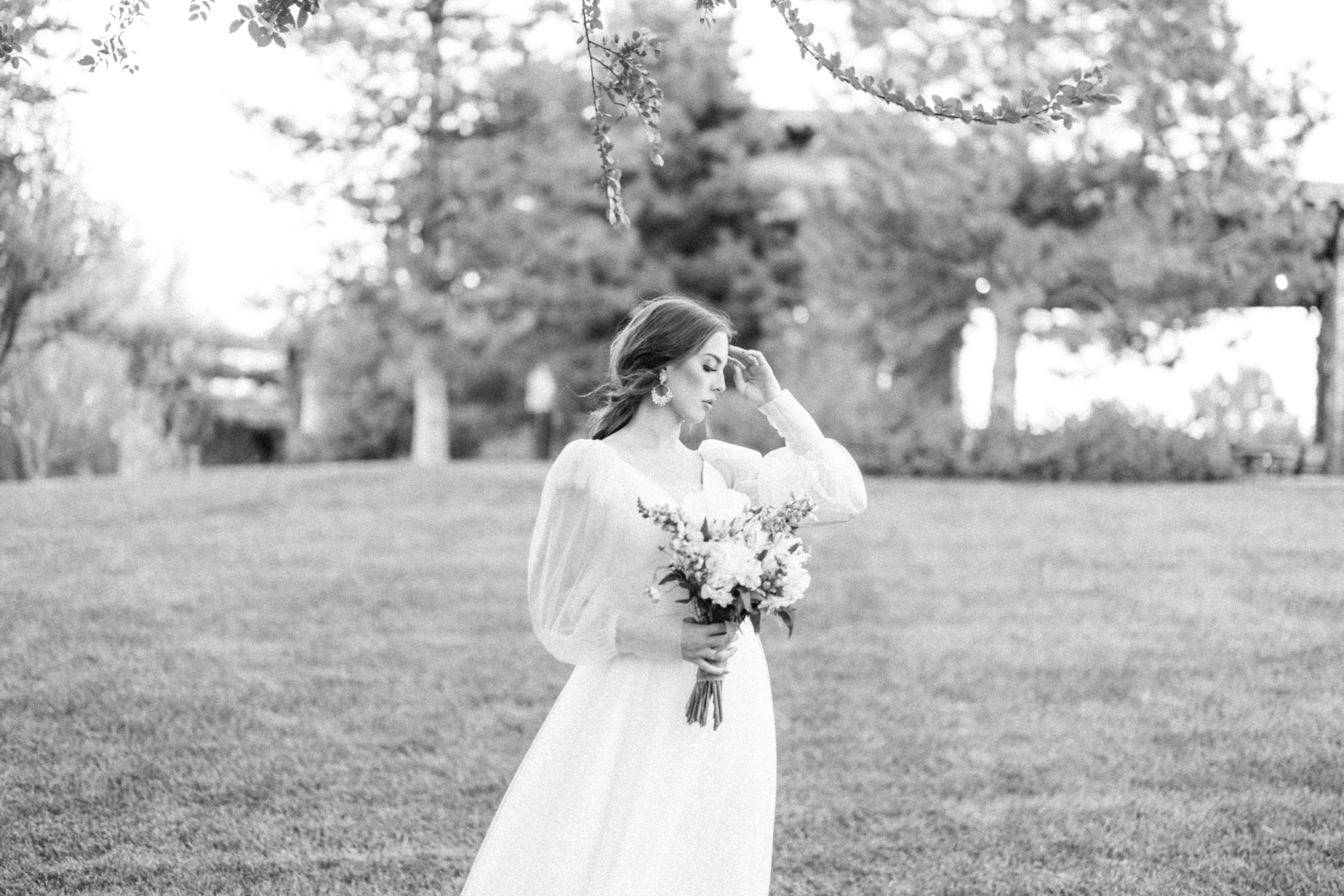 black and white photo of a bride holding a bouquet wearing a long sleeve wedding dress 
